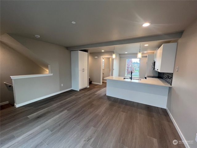 kitchen with white cabinets, sink, hanging light fixtures, dark hardwood / wood-style floors, and kitchen peninsula