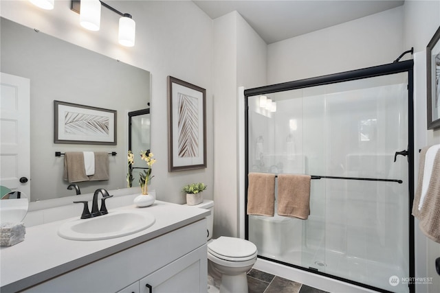 bathroom with an enclosed shower, vanity, toilet, and tile patterned flooring