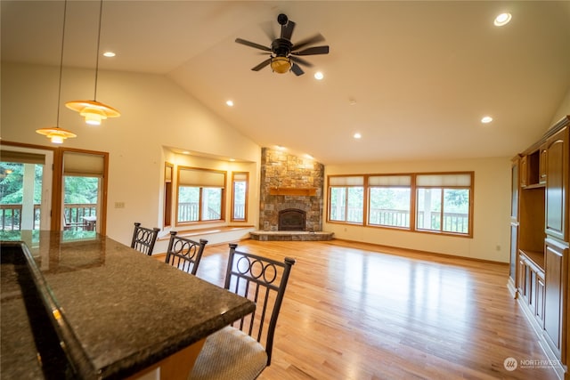 dining space featuring plenty of natural light, ceiling fan, a stone fireplace, and light hardwood / wood-style flooring