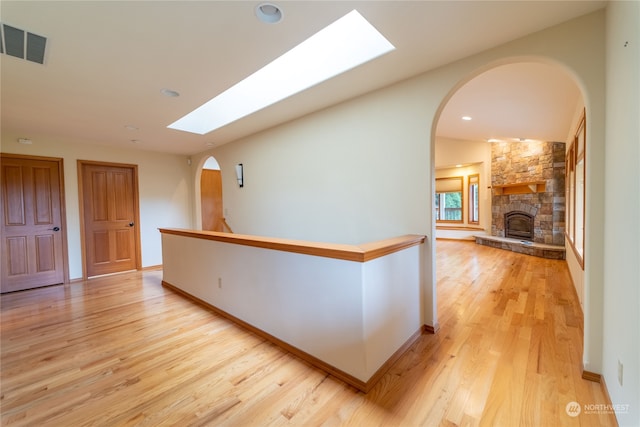 hallway with a skylight and light wood-type flooring