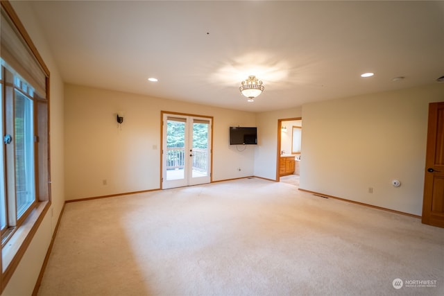 carpeted spare room featuring french doors