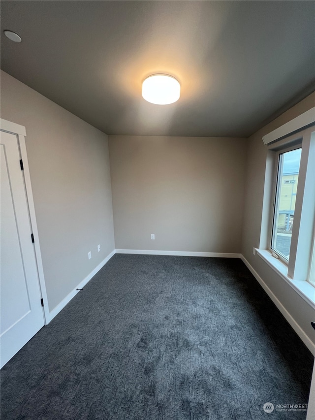 unfurnished room with dark colored carpet