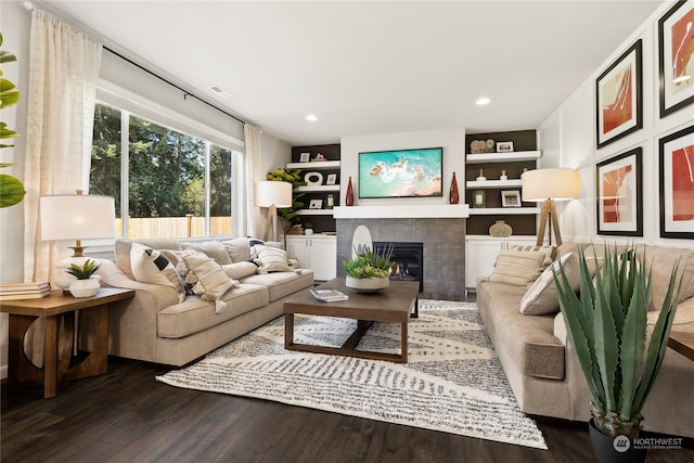 living room with dark hardwood / wood-style flooring, a tile fireplace, and built in features