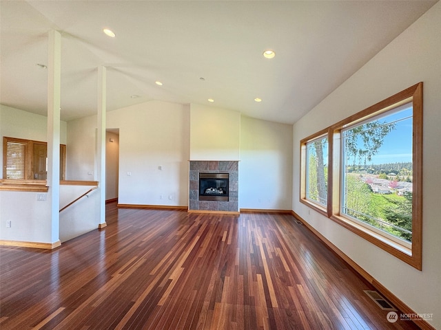 unfurnished living room with lofted ceiling, dark hardwood / wood-style flooring, and a tile fireplace