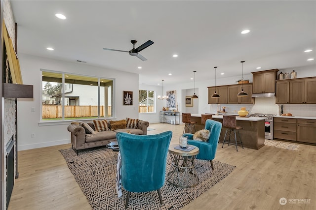 living room with ceiling fan with notable chandelier and light wood-type flooring