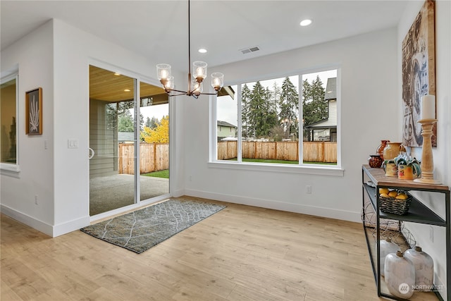 doorway to outside featuring an inviting chandelier and light wood-type flooring