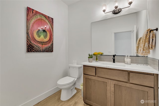 bathroom with wood-type flooring, vanity, tasteful backsplash, and toilet