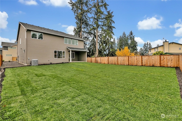 rear view of property with a lawn and central air condition unit