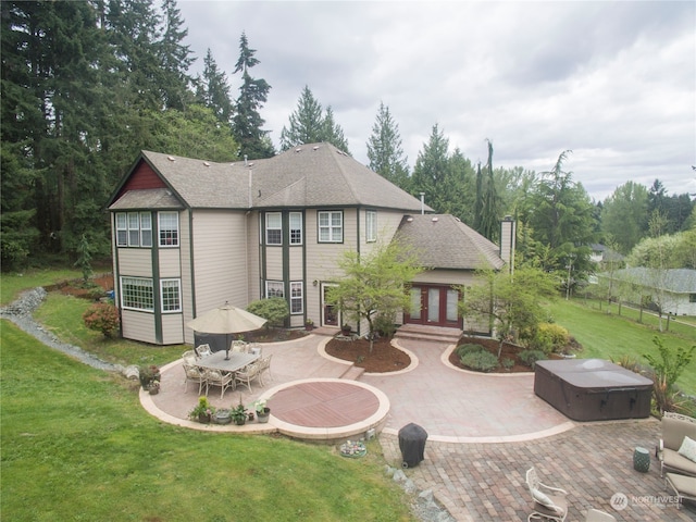 back of house featuring a yard, a patio area, and a hot tub