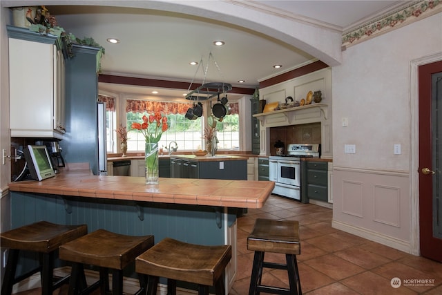 kitchen with kitchen peninsula, white cabinets, stainless steel dishwasher, a breakfast bar area, and double oven range