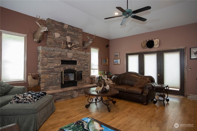 living room with plenty of natural light, a fireplace, ceiling fan, and light wood-type flooring