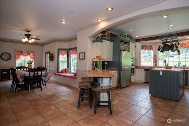 tiled dining space featuring ceiling fan, crown molding, and a healthy amount of sunlight