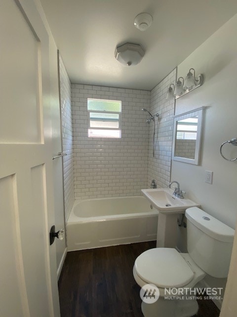 bathroom with tiled shower / bath combo, hardwood / wood-style floors, and toilet