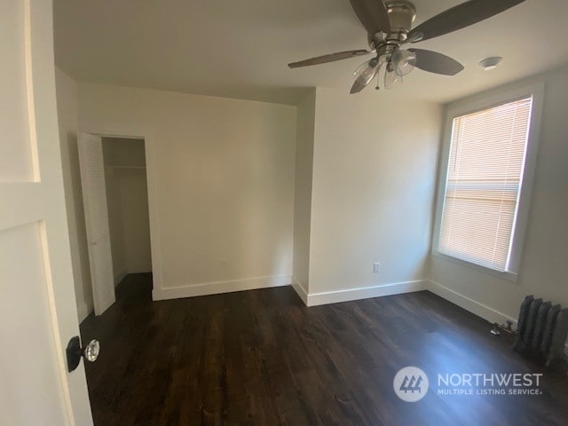 empty room featuring plenty of natural light, dark hardwood / wood-style floors, and ceiling fan