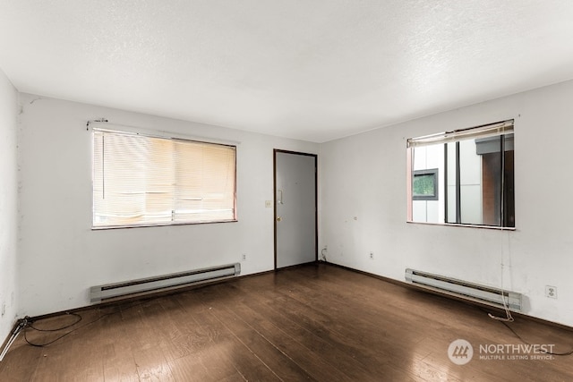 empty room featuring baseboard heating and dark hardwood / wood-style flooring