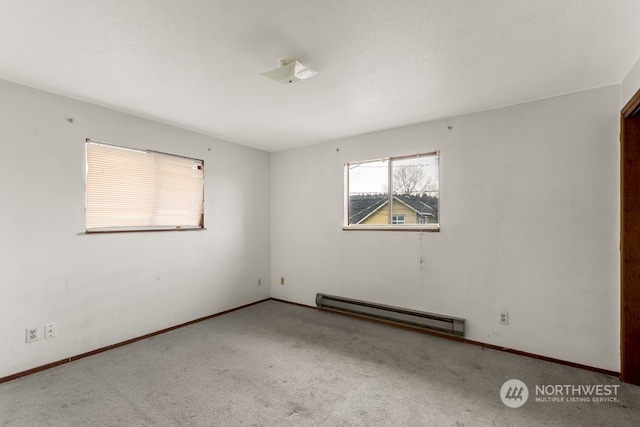 carpeted empty room featuring a baseboard heating unit