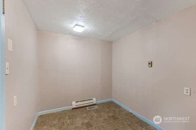 laundry room with dark tile floors, a baseboard radiator, and a textured ceiling