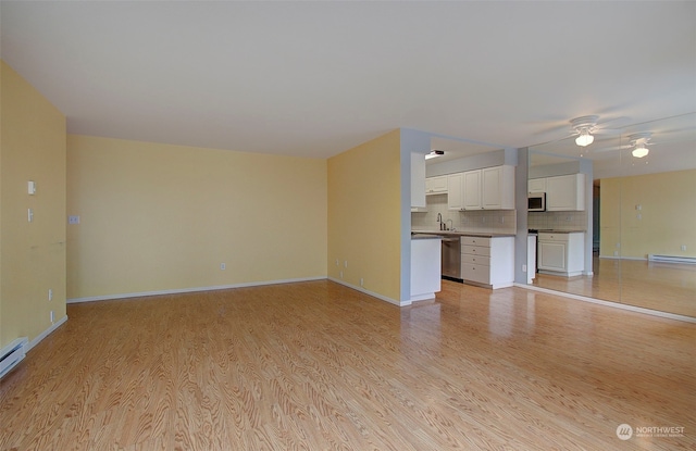 unfurnished living room with a baseboard radiator, light hardwood / wood-style flooring, and sink