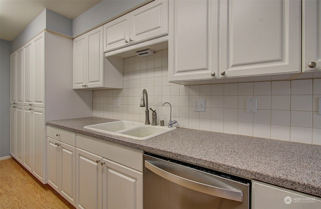 kitchen featuring decorative backsplash, white cabinets, sink, and stainless steel dishwasher