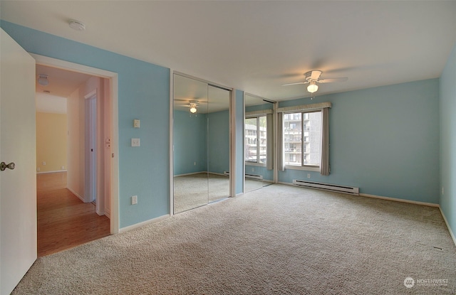 unfurnished bedroom featuring light carpet, baseboard heating, multiple closets, and ceiling fan