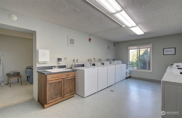 laundry area with independent washer and dryer, sink, and a textured ceiling