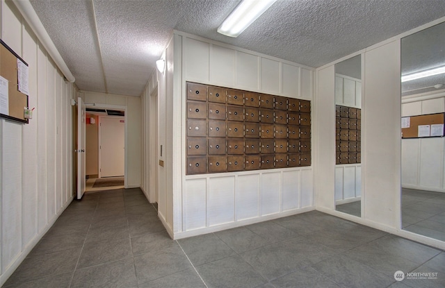 hallway with mail boxes, tile patterned flooring, and a textured ceiling