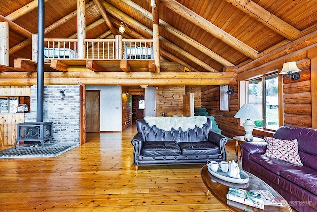 living room featuring hardwood / wood-style flooring, high vaulted ceiling, a wood stove, and beam ceiling