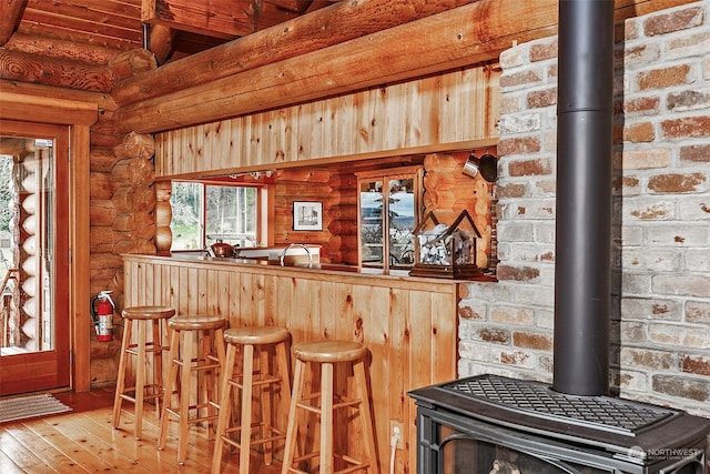 bar featuring hardwood / wood-style floors, rustic walls, and a wood stove