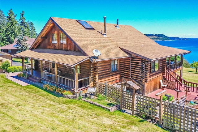 back of property featuring a water view, covered porch, and a lawn