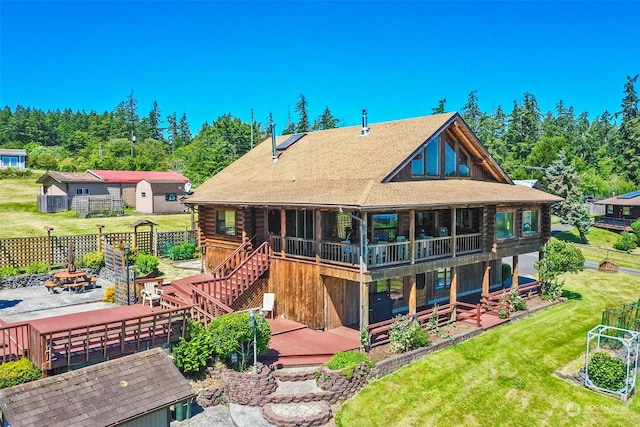 rear view of property featuring a storage shed, a lawn, a patio, a deck, and a fire pit