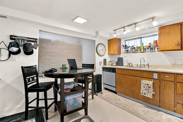 kitchen featuring track lighting, dishwasher, sink, and light tile flooring