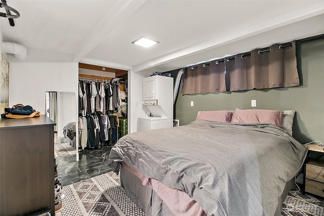 bedroom with stacked washer and clothes dryer, a closet, beam ceiling, and dark tile flooring