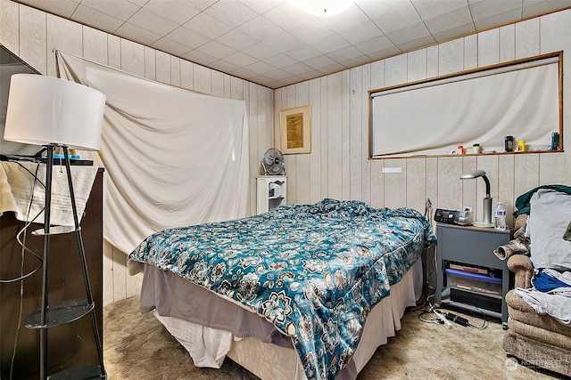 bedroom with light carpet and wood walls