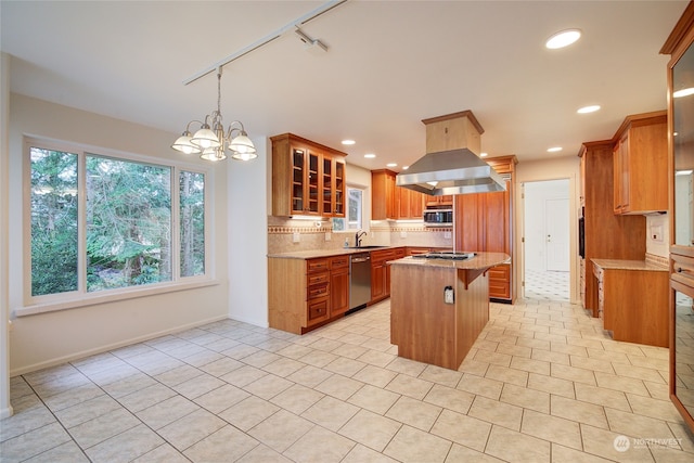 kitchen with appliances with stainless steel finishes, rail lighting, decorative backsplash, a kitchen island, and light tile patterned floors