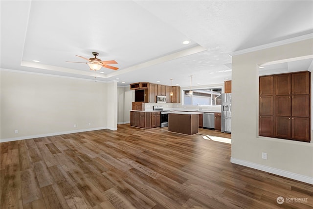 unfurnished living room featuring a raised ceiling, ceiling fan, sink, and dark wood-type flooring