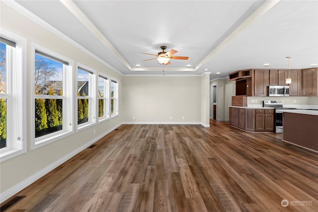 unfurnished living room with a raised ceiling, ceiling fan, dark hardwood / wood-style flooring, and crown molding