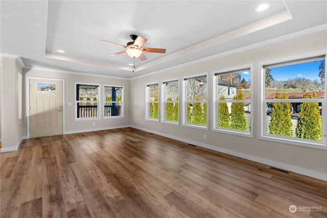 unfurnished sunroom featuring ceiling fan and a tray ceiling