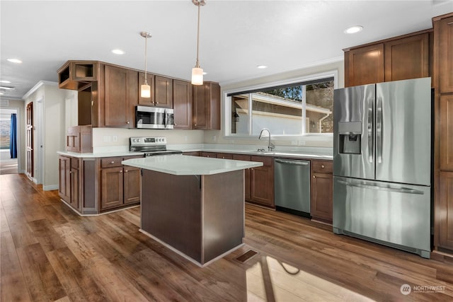 kitchen with stainless steel appliances, crown molding, dark wood-type flooring, pendant lighting, and a center island