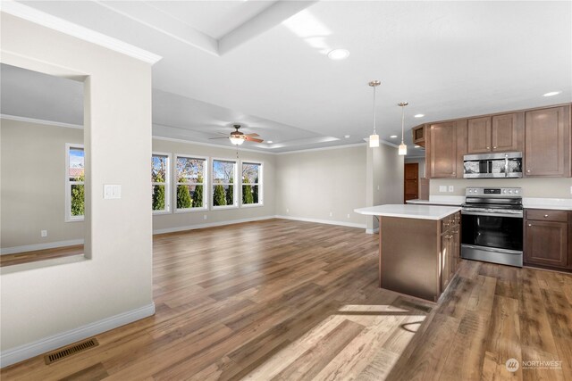 kitchen with hardwood / wood-style floors, a center island, ceiling fan, appliances with stainless steel finishes, and decorative light fixtures