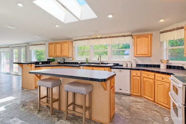 kitchen featuring a center island, white appliances, a skylight, and tile countertops