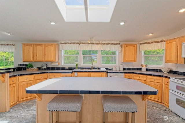 kitchen with white appliances, plenty of natural light, a center island, and a skylight