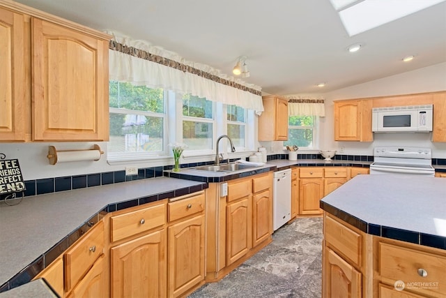 kitchen with white appliances, sink, lofted ceiling with skylight, and light brown cabinetry