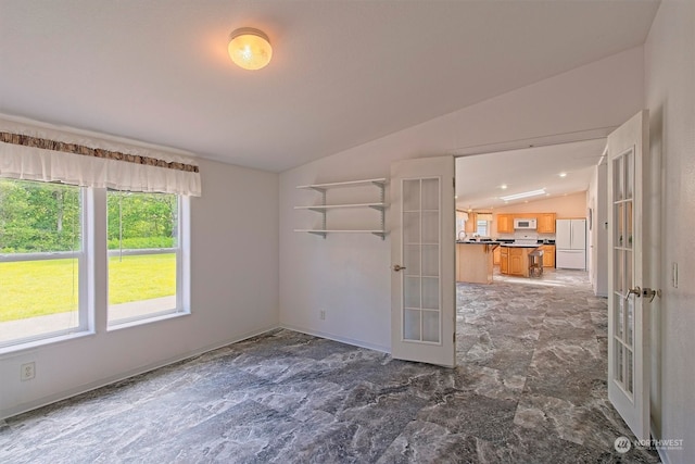 spare room with tile floors, french doors, and vaulted ceiling