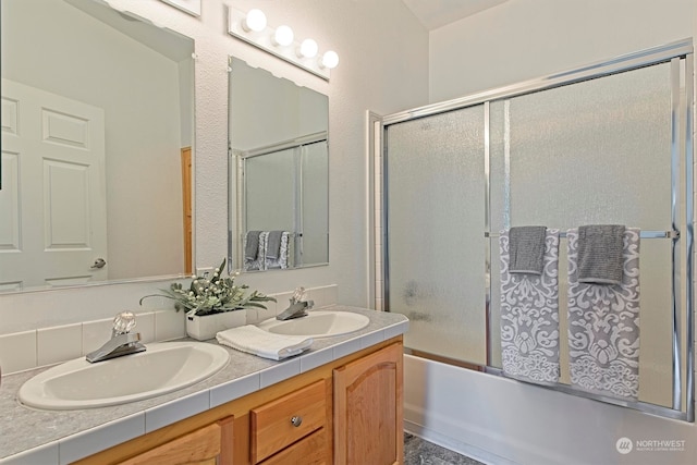 bathroom with shower / bath combination with glass door, double sink, and oversized vanity