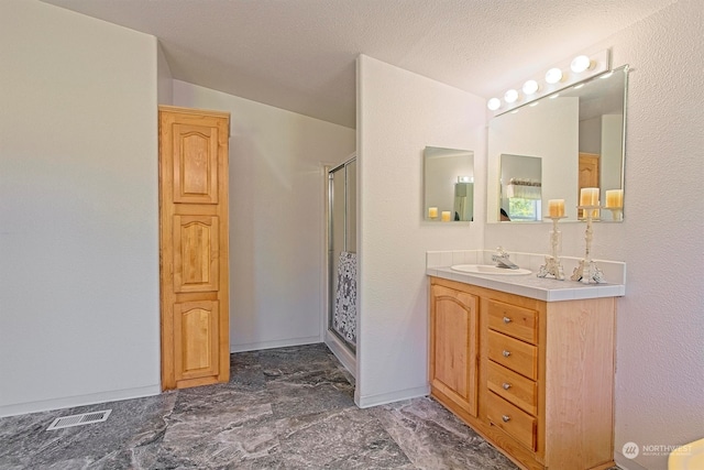 bathroom with tile flooring, a shower with door, a textured ceiling, and large vanity