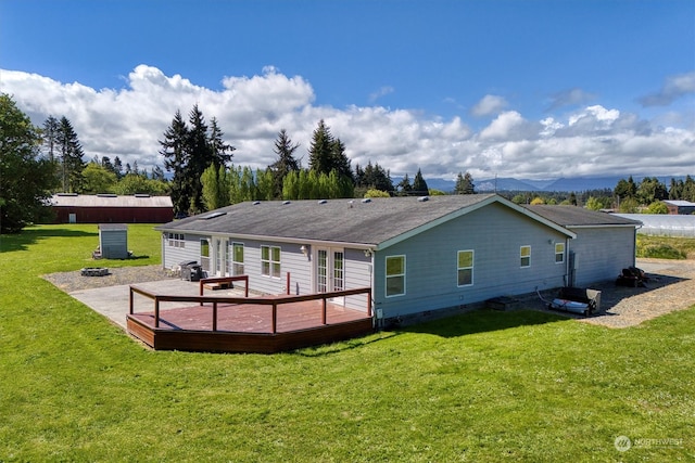 back of property with a wooden deck and a lawn