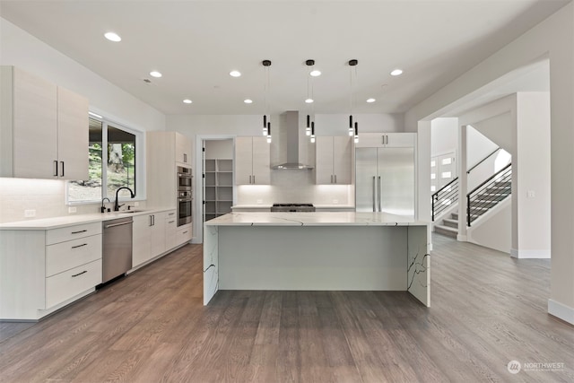 kitchen with hardwood / wood-style flooring, appliances with stainless steel finishes, decorative backsplash, and wall chimney exhaust hood