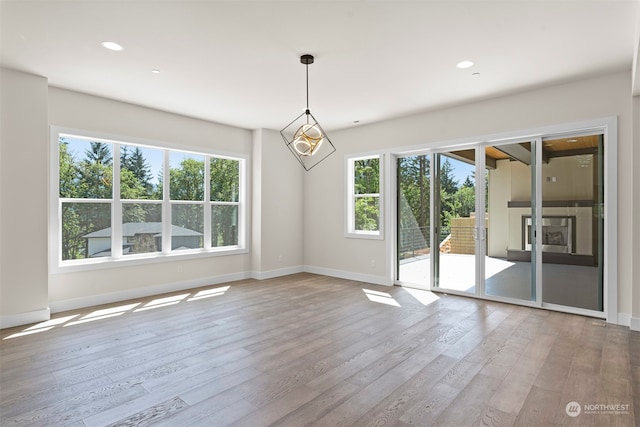 unfurnished room featuring an inviting chandelier, wood-type flooring, and a wealth of natural light