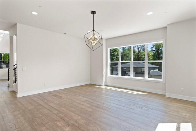 unfurnished room with light hardwood / wood-style flooring and a chandelier