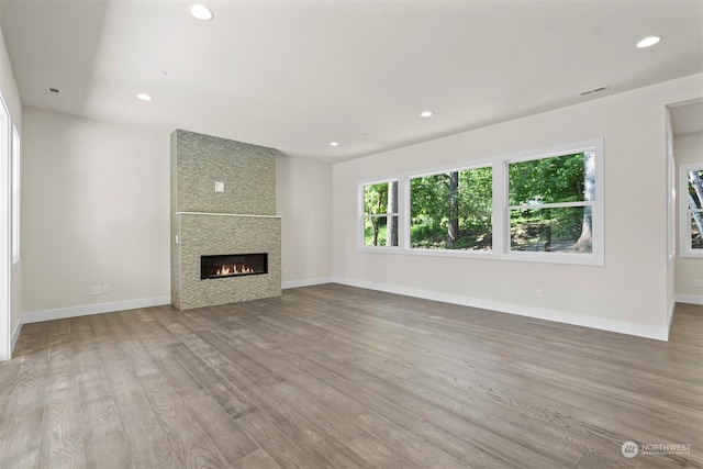 unfurnished living room with wood-type flooring and a large fireplace